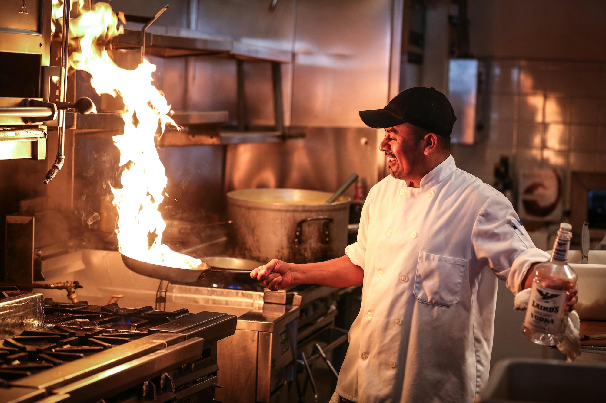 Chef cooking over a commercial gas range with rising flame
